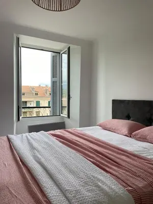 a white bedroom with a bed and a window at Appartement Corte centre ville in Corte