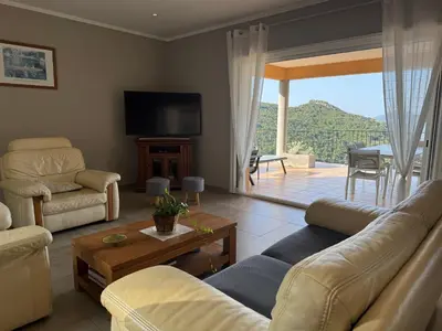 a living room with a couch and a table and a tv at Gîte Inseme, le calme entre mer et montagne en Corse in Arbellara