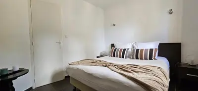 a bedroom with a large bed with white walls at T2 Résidence Dolce & Vita B4 vue mer et piscine in Propriano