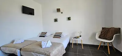 a bedroom with two beds and a tv and a chair at T2 Résidence Dolce & Vita B4 vue mer et piscine in Propriano
