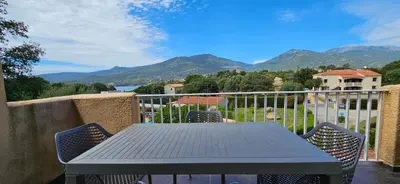a table and chairs on a balcony with mountains at T2 Résidence Dolce & Vita B4 vue mer et piscine in Propriano