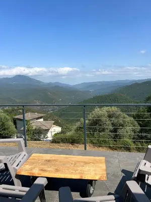 a wooden table on a balcony with a view of mountains at Villa H in Casanova