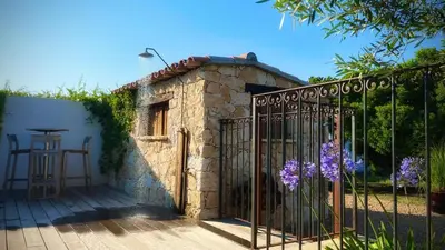 a gate to a stone house with purple flowers at Villa Maestro Maria Charme Confort et Accueil Chaleureux à 5 min de la plage in Lecci