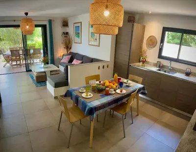 a kitchen and living room with a table and chairs at Villa Maestro Maria Charme Confort et Accueil Chaleureux à 5 min de la plage in Lecci