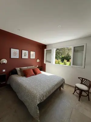 a bedroom with a large bed and a window at Rez-de-villa avec terrasse privative sur jardin in Ajaccio