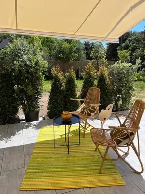 a patio with two chairs and a table on a rug at Rez-de-villa avec terrasse privative sur jardin in Ajaccio