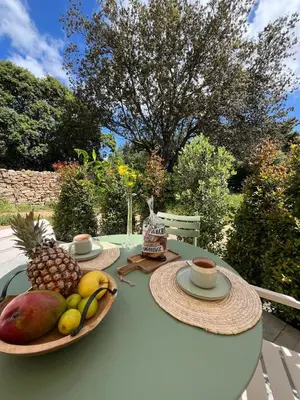 a table with two plates of fruit and a cup of coffee at Rez-de-villa avec terrasse privative sur jardin in Ajaccio