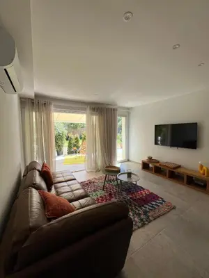 a living room with a couch and a flat screen tv at Rez-de-villa avec terrasse privative sur jardin in Ajaccio