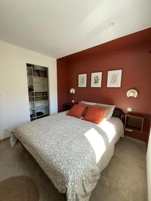 a bedroom with a large bed with red walls at Rez-de-villa avec terrasse privative sur jardin in Ajaccio
