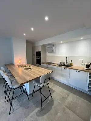 a large kitchen with a wooden table and chairs at Rez-de-villa avec terrasse privative sur jardin in Ajaccio