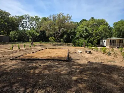 a field of dirt with a house in the background at La Vigne in Lecci