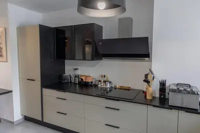 a kitchen with white cabinets and a black counter top at Sagone Appartement T3 in Coggia