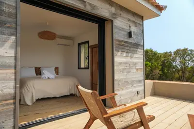 a room with a bed and a chair on a deck at Bergerie entre plage et maquis in Zonza