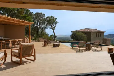a patio with chairs and a pool with a view at Bergerie entre plage et maquis in Zonza