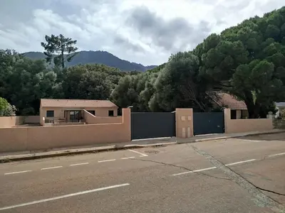 a building on the side of a road with a fence at Clos Jeannette Villa près de la plage de Pinarelle et des piscines naturelles du Cavu in Zonza
