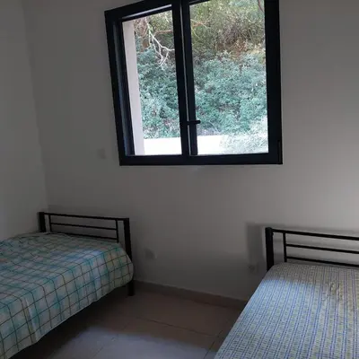 two beds in a room with a window at Clos Jeannette Villa près de la plage de Pinarelle et des piscines naturelles du Cavu in Zonza