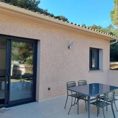 a patio with a table and chairs next to a building at Clos Jeannette Villa près de la plage de Pinarelle et des piscines naturelles du Cavu in Zonza