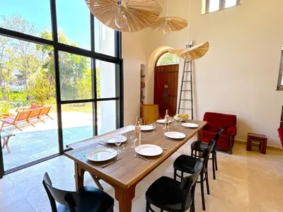 a dining room table with chairs and a large window at Villa Padulone in Aléria