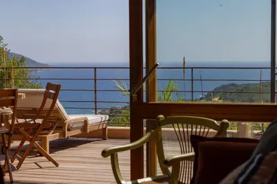 a balcony with chairs and a table and a view of the ocean at Signura, maison entre mer et maquis in Piana