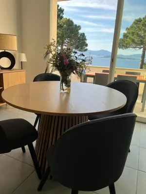 a table with chairs and a vase with flowers on it at La villa Timeo in Pietrosella