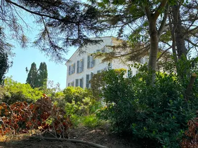 a large white building with trees and bushes at L'appartement Vicente in Aléria