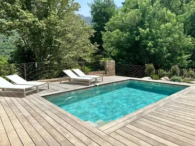 a swimming pool on a wooden deck with two lounge chairs at Casa di l'Ortu - Villa neuve avec piscine privée chauffée in Feliceto