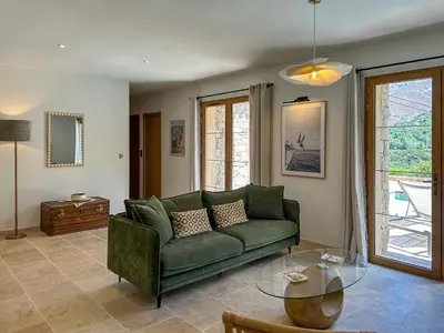 a living room with a green couch and a glass table at Casa di l'Ortu - Villa neuve avec piscine privée chauffée in Feliceto