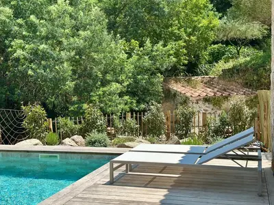 a bench sitting on a deck next to a swimming pool at Casa di l'Ortu - Villa neuve avec piscine privée chauffée in Feliceto