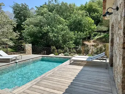 a swimming pool with two chairs and a wooden deck at Casa di l'Ortu - Villa neuve avec piscine privée chauffée in Feliceto