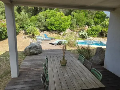 a wooden deck with a table and chairs next to a pool at Maison climatisée de 3 chambres avec piscine privée in Sotta
