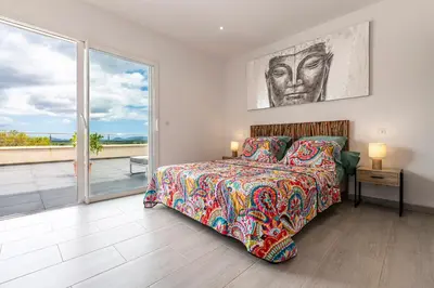 a bedroom with a bed and a view of the ocean at Maison Mawie - Vue montagne piscine jacuzzi in Sotta