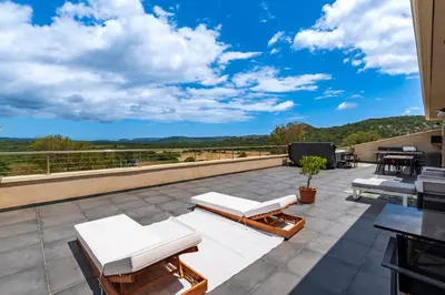 a patio with white chairs and a television on a roof at Maison Mawie - Vue montagne piscine jacuzzi in Sotta