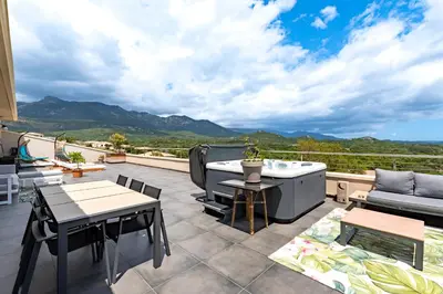 a patio with a tub and a table and chairs at Maison Mawie - Vue montagne piscine jacuzzi in Sotta
