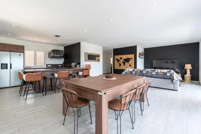 a kitchen and living room with a wooden table and chairs at Maison Mawie - Vue montagne piscine jacuzzi in Sotta