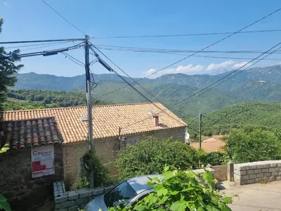 a car parked in front of a house with mountains in the background at maison de village in Carbuccia