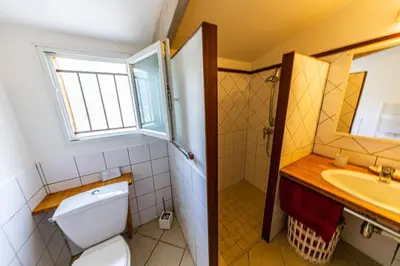 a bathroom with a toilet and a sink and a window at Le Cabanon by Pinarello Villa Services in Zonza