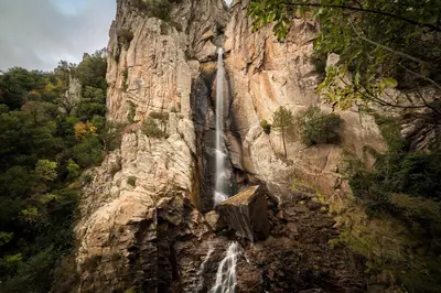 a waterfall on the side of a rocky mountain at Le Cabanon by Pinarello Villa Services in Zonza