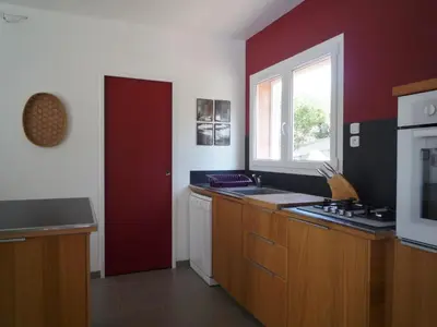 a kitchen with wooden cabinets and a red wall at Canopee by Pinarello Villa Services in Zonza