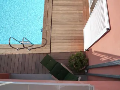 a green bench sitting on a porch next to a pool at Canopee by Pinarello Villa Services in Zonza