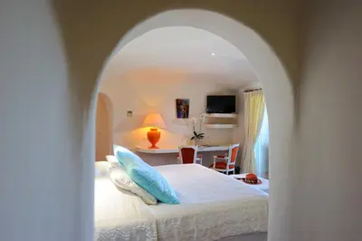 a bedroom with a white bed with blue pillows at Hôtel Marina di cavu in Bonifacio