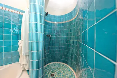 a blue tiled shower with a fan in a bathroom at Hôtel Marina di cavu in Bonifacio