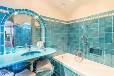 a blue tiled bathroom with a sink and a tub at Hôtel Marina di cavu in Bonifacio