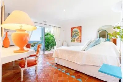 a bedroom with a bed and a desk with a lamp at Hôtel Marina di cavu in Bonifacio