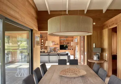 a dining room with a wooden table and a large light fixture at Villa Lavezzi in Bonifacio