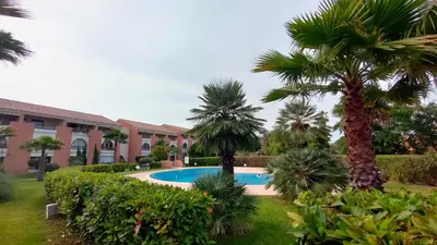 a resort with a swimming pool and palm trees at Appartamento climatizzato di 42 mq a Marina di Bravone a 200m dalla spiaggia in Linguizzetta