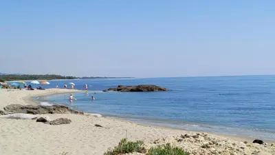 a beach with people on the sand and the ocean at Appartamento climatizzato di 42 mq a Marina di Bravone a 200m dalla spiaggia in Linguizzetta