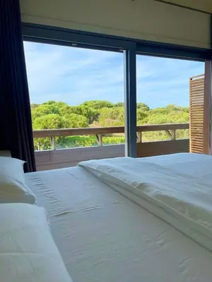 a bedroom with a white bed and a large window at Apartments PETIT DOMAIN DE SPERONE in Bonifacio
