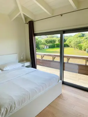 a bedroom with a bed and a large window at Apartments PETIT DOMAIN DE SPERONE in Bonifacio