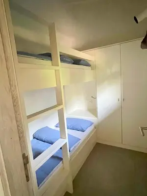 a room with two bunk beds with blue sheets at Apartments PETIT DOMAIN DE SPERONE in Bonifacio