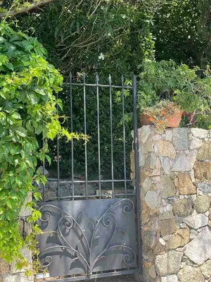 a metal gate in front of a stone wall at Historic Villa In Sant Antonino With Sea Views in SantʼAntonino